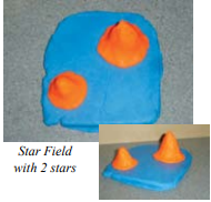 Blue clay in a flat rectangle with two orange pieces of clay in cone shapes on top.